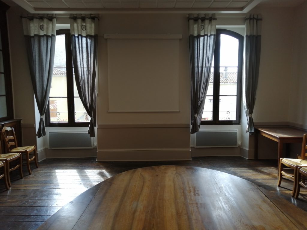 Photographie d'une pièce avec deux grandes fenêtres et rideaux